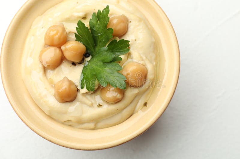 Köstlicher Hummus mit Petersilie und Kichererbsen in Schüssel auf weißem Tisch oben Ansicht lizenzfreies stockbild