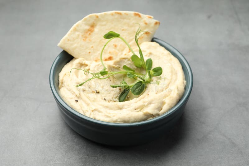 Köstlicher Hummus in Schüssel und Pita auf grauem Tisch in der Nähe stockfotos