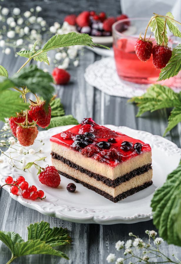 Köstlicher Moussekuchen mit Beerengelee auf grauem Boden mit Tasse Saft Beeren und Blumen. Süßigkeiten stockbild