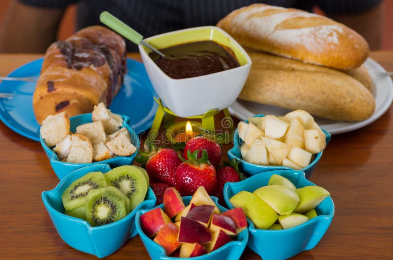 Köstliches Schokoladenfondue innerhalb einer weißen Schüssel mit sortierten Früchten wie, Erdbeere, Birne, Kiwi, Apfel und Stücke stockfotografie Köstliches Schokoladenfondue innerhalb einer weißen Schüssel mit sortierten Früchten wie, Erdbeere, Birne, Kiwi, Apfel und Stücke stockfotografie