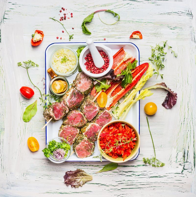 Köttsteknålar med nya bitande grönsaker och smaktillsats på emaljplattan Köttsteknålar för gallret eller matlagning, förberedelse arkivfoto