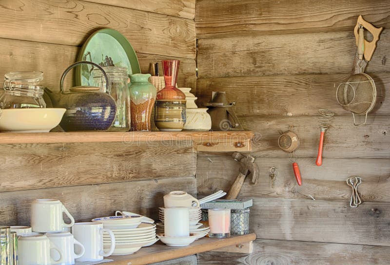 A still life image of kitchecn shelves in an old log cabin showing the plates, cups, bowls and other houswares arranged on each shelf. A still life image of kitchecn shelves in an old log cabin showing the plates, cups, bowls and other houswares arranged on each shelf.