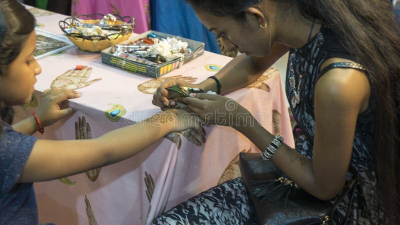 Künstler, der Hennastrauchtätowierung auf Kinderhand anwendet stockbilder Künstler, der Hennastrauchtätowierung auf Kinderhand anwendet stockbilder
