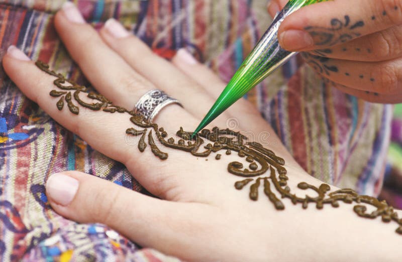 Künstler, der traditionelle indische Hennastrauchtätowierung auf Frauenhand malt lizenzfreie stockbilder Künstler, der traditionelle indische Hennastrauchtätowierung auf Frauenhand malt lizenzfreie stockbilder