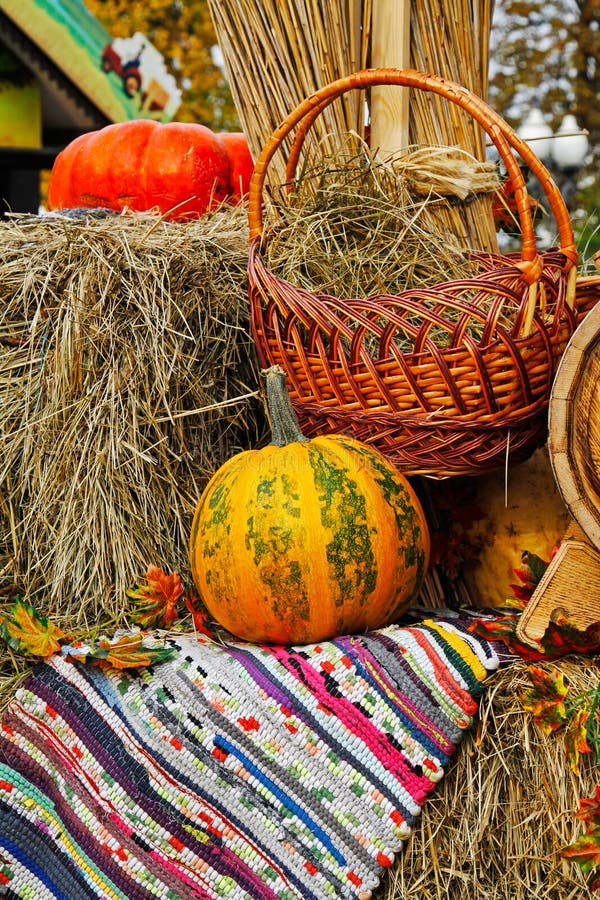 Kürbis mit Weidenkorb und Wolldecke auf Stroh am Marktplatz lizenzfreie stockfotos Kürbis mit Weidenkorb und Wolldecke auf Stroh am Marktplatz lizenzfreie stockfotos