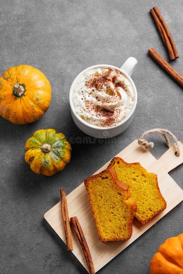 Kürbiskuchen mit Zimt auf einem Holzbrett auf dunklem Hintergrund mit dekorativen Kürbissen und einer Tasse heißem Kürbis lizenzfreies stockbild