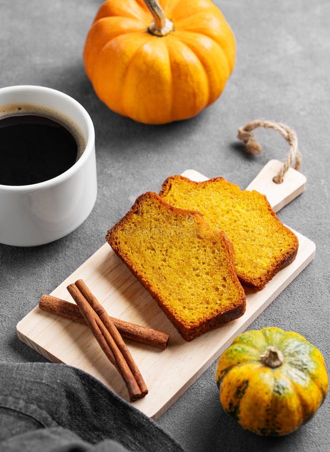 Kürbiskuchen mit Zimt auf einem Holzbrett auf dunklem Hintergrund mit dekorativen Kürbissen und einer Tasse Kaffee stockfotos