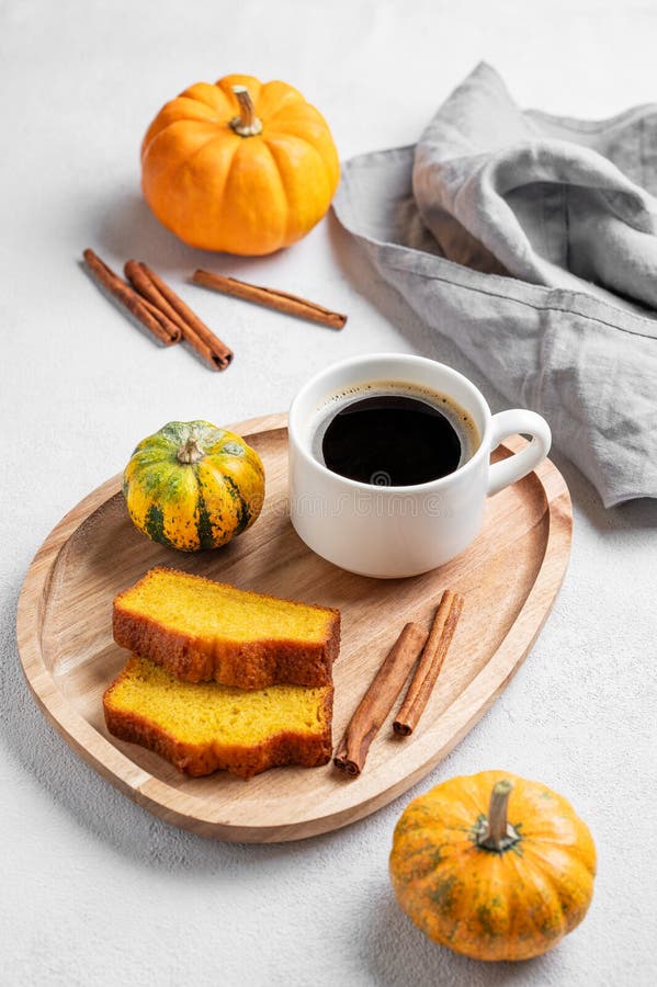 Kürbiskuchen mit Zimt auf einem Holzbrett auf hellem Hintergrund mit dekorativen Kürbissen und einer Tasse Kaffee lizenzfreies stockbild
