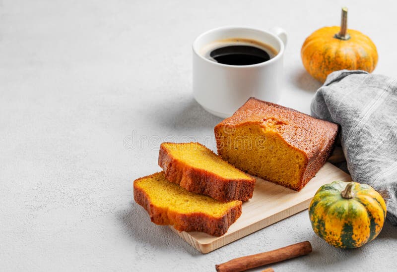 Kürbiskuchen mit Zimt auf einem Holzbrett auf hellem Hintergrund mit dekorativen Kürbissen und einer Tasse Kaffee stockfoto