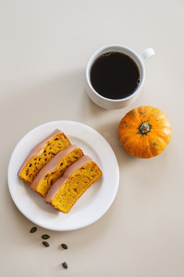 Kürbiskuchen oder Kuchen mit Eis auf einem Teller auf einem hellen Hintergrund mit dekorativem Kürbis und einer Tasse Kaffee lizenzfreies stockfoto