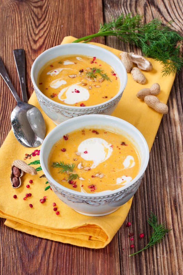 Kürbissuppe mit Erdnüssen auf einem Holztisch stockfotos
