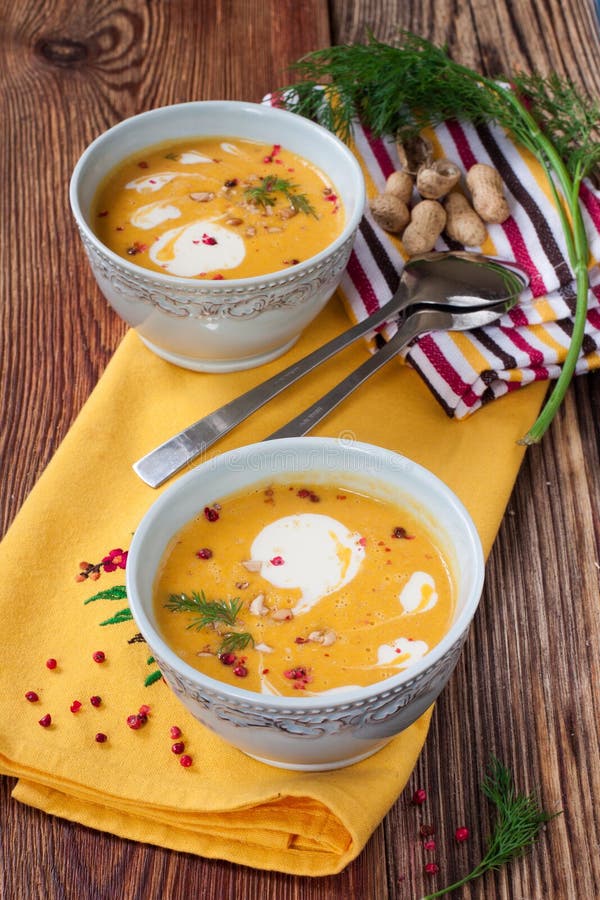 Kürbissuppe mit Erdnüssen auf einem Holztisch stockbilder