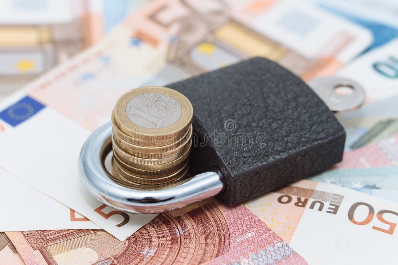 Image of a padlock with coins in the open space on a background of bank notes. Keeping your money safe and secure. Image of a padlock with coins in the open space on a background of bank notes. Keeping your money safe and secure.