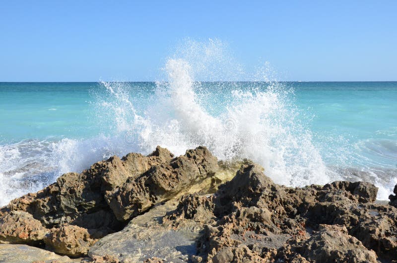 L'acqua dell'oceano blu si spruzza su rocce sulla spiaggia