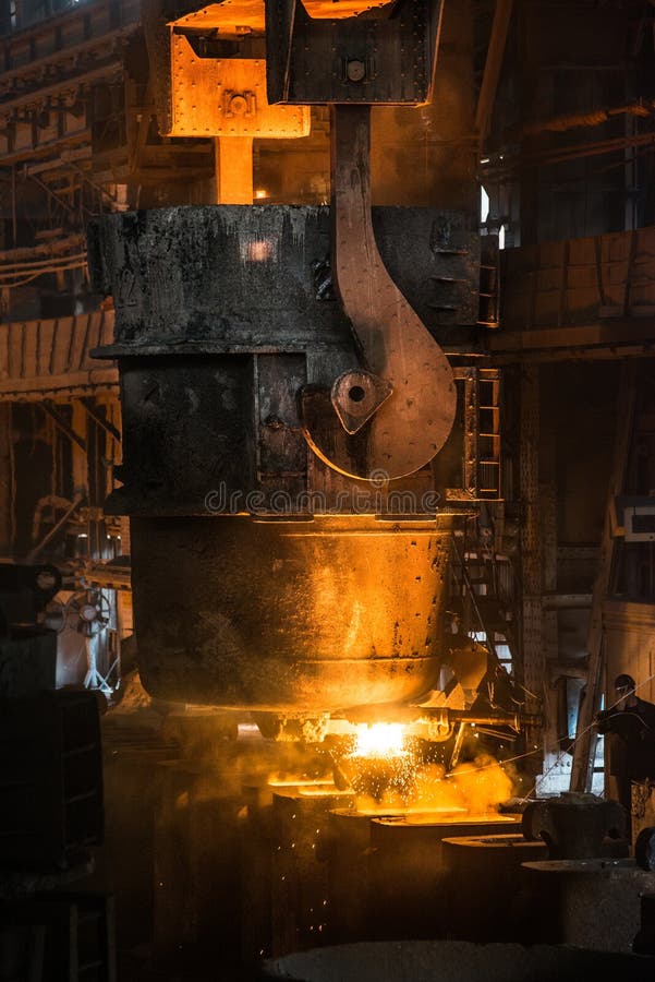 L'addetto alla lavorazione dell'acciaio cola il metallo liquido negli stampi dal carro armato fotografie stock libere da diritti L'addetto alla lavorazione dell'acciaio cola il metallo liquido negli stampi dal carro armato fotografie stock libere da diritti