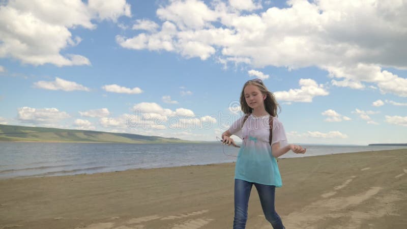 L'adolescent saute le long de la plage et écoute la musique clips vidéos