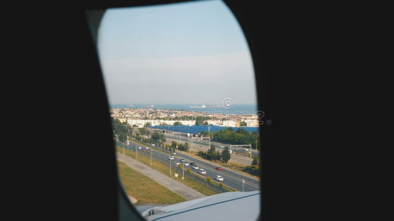 L'aeroplano sta atterrando sopra la bella città di spiaggia soleggiata dell'estate, stupendo la vista della città e dell'ala at