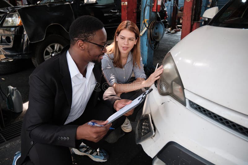 L'agent d'assurance homme noir explique au client la réclamation de voiture au garage. images stock
