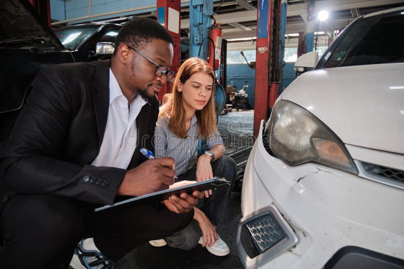 L'agent d'assurance homme noir explique au client la réclamation de voiture au garage. images libres de droits