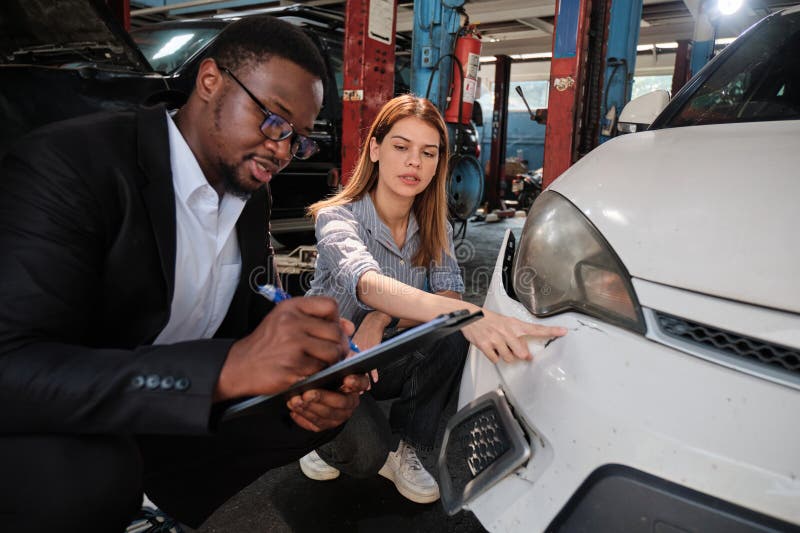 L'agent d'assurance homme noir explique au client la réclamation de voiture au garage. image libre de droits