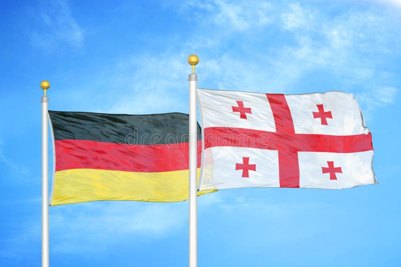 L'Allemagne et la Géorgie deux drapeaux sur les mâts de drapeau et le ciel nuageux bleu.