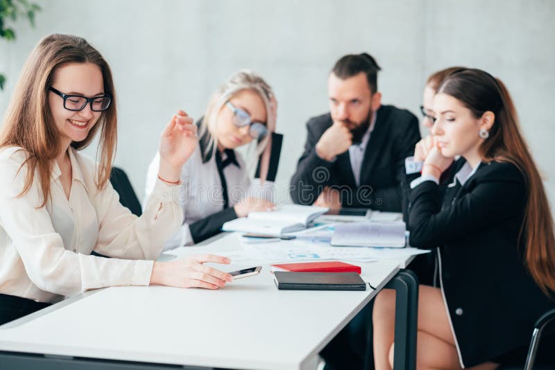 Idle employee. Team member slacking off. Smiling women browsing smartphone at workplace. Idle employee. Team member slacking off. Smiling women browsing smartphone at workplace.