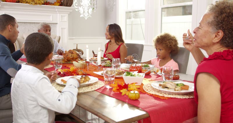 L'appareil-photo dépiste pour montrer le famille étendu s'asseyant autour de la table pour le repas de thanksgiving