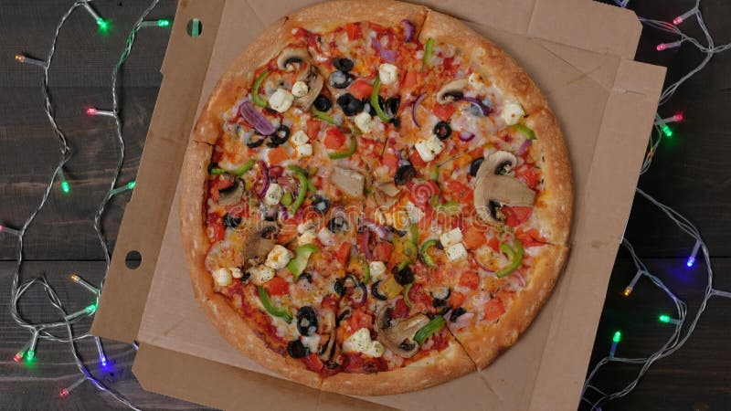 L'appetitosa pizza italiana con verdure ruota sulla decorazione natalizia.
