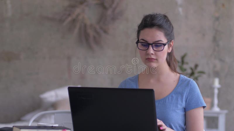 L'apprentissage en ligne, fille moderne dans des lunettes regarde dans l'écran d'ordinateur portable et les types textotent sur