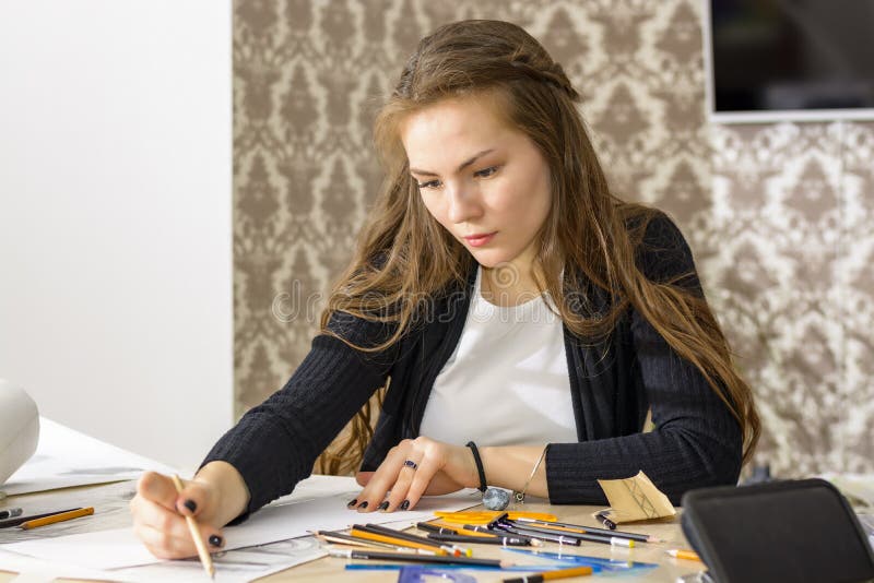 L'architetto della donna disegna un piano, la progettazione, forme geometriche dalla matita sul grande foglio di carta alla scriv fotografie stock L'architetto della donna disegna un piano, la progettazione, forme geometriche dalla matita sul grande foglio di carta alla scriv fotografie stock
