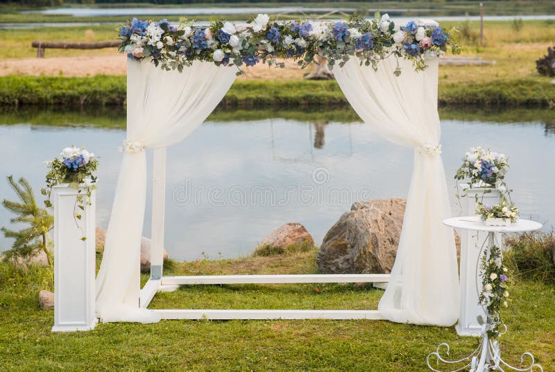 L'arco di nozze è decorato con i fiori e la seta blu della luce bianca Cerimonia di nozze di estate fotografia stock libera da diritti L'arco di nozze è decorato con i fiori e la seta blu della luce bianca Cerimonia di nozze di estate fotografia stock libera da diritti