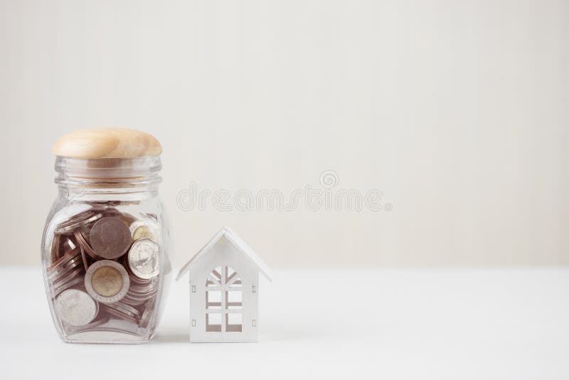 L'argent de l'épargne invente dans le pot en verre avec la maison blanche modèle sur la table en bois Investissement de propriété photos libres de droits L'argent de l'épargne invente dans le pot en verre avec la maison blanche modèle sur la table en bois Investissement de propriété photos libres de droits