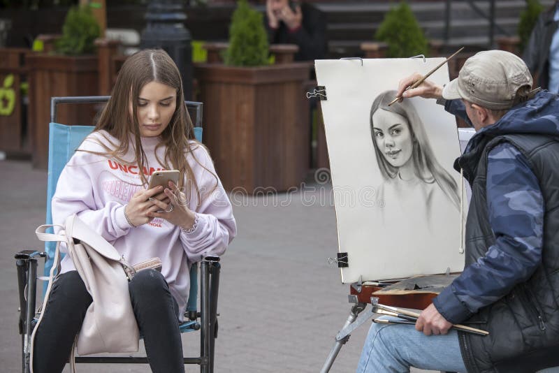 L'artista della via dipinge il ritratto di una ragazza sulle vie di Mosca fotografia stock L'artista della via dipinge il ritratto di una ragazza sulle vie di Mosca fotografia stock