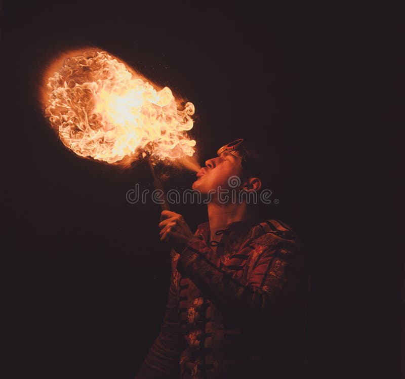 L'artista di manifestazione del fuoco respira il fuoco nello scuro