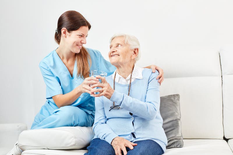 L'assistente di professione d'infermiera d? ad anziano un bicchiere d'acqua immagini stock libere da diritti L'assistente di professione d'infermiera d? ad anziano un bicchiere d'acqua immagini stock libere da diritti