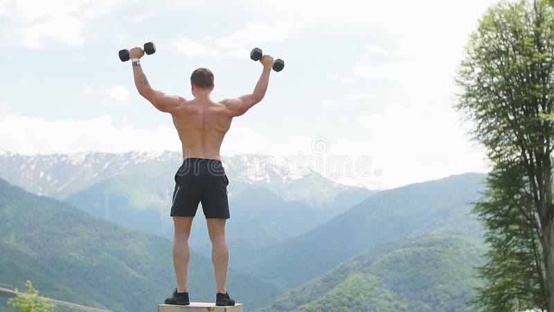 L'athlète masculin musculaire avec des bras a soulevé faire les haltères de levage d'exercices