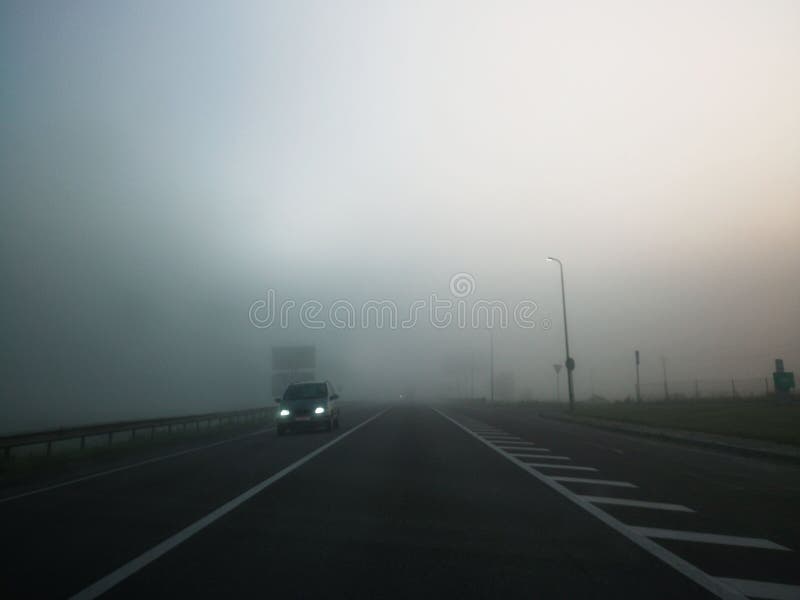 L'auto va per strada nella nebbia Le auto viaggiano veloci su un'autostrada in un giorno di nebbia Concetto di problema di sicure fotografia stock L'auto va per strada nella nebbia Le auto viaggiano veloci su un'autostrada in un giorno di nebbia Concetto di problema di sicure fotografia stock