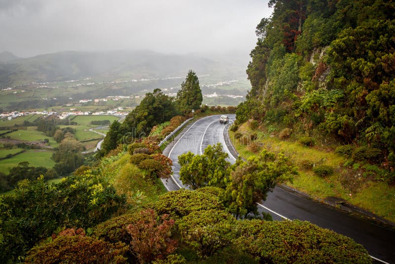 L'automobile al accende una strada bagnata nelle montagne fotografia stock libera da diritti L'automobile al accende una strada bagnata nelle montagne fotografia stock libera da diritti