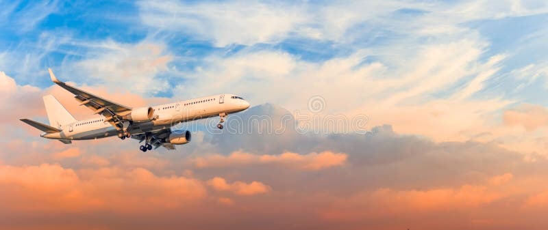 L'avion de passager est vitesse d'approche d'atterrissage libérée, contre des nuages de ciel de coucher du soleil, panorama Aviat