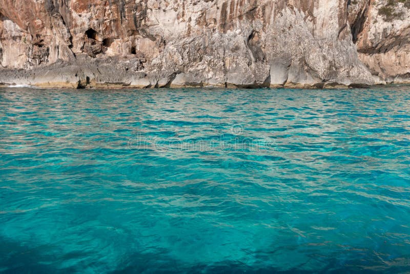 L'eau colorée par turquoise devant la falaise côtière photo stock L'eau colorée par turquoise devant la falaise côtière photo stock