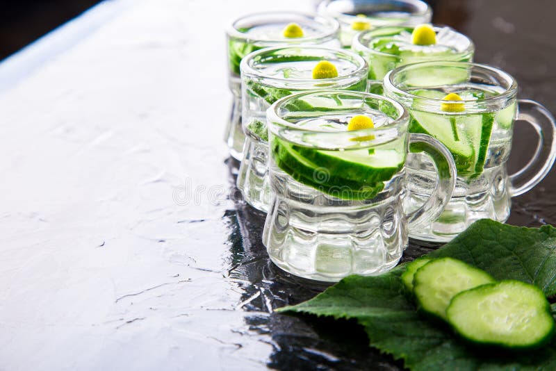 L'eau de concombre dans six pots en verre de petit maçon sur le fond noir images stock L'eau de concombre dans six pots en verre de petit maçon sur le fond noir images stock