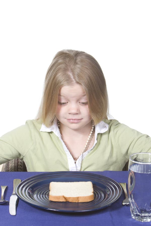 Young girl in disbelief about her bread and water dinner. Young girl in disbelief about her bread and water dinner.