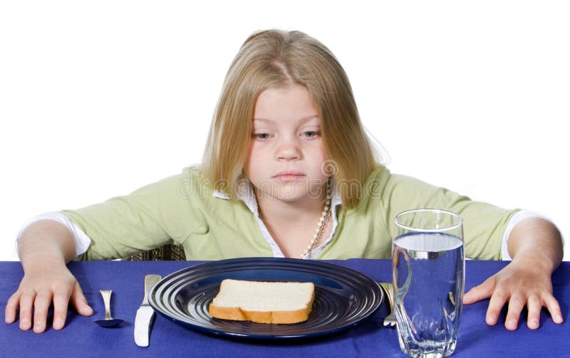 Young girl in disbelief about her bread and water dinner. Young girl in disbelief about her bread and water dinner.