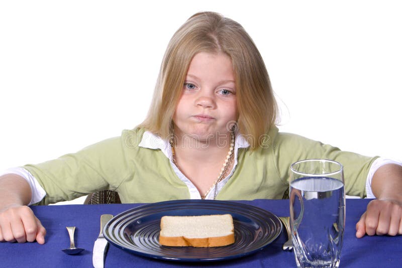 Young girl showing unhappy acceptance of her bread and water dinner. Young girl showing unhappy acceptance of her bread and water dinner.