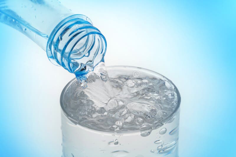 L'eau de versement de la bouteille dans le verre sur le fond bleu photo stock L'eau de versement de la bouteille dans le verre sur le fond bleu photo stock