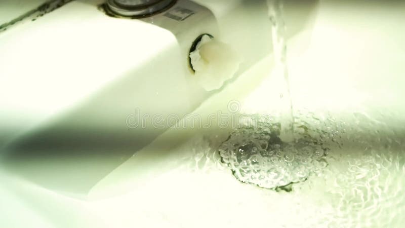 L'eau qui coule vers l'évier blanc du robinet à côté des mains des femmes clips vidéos
