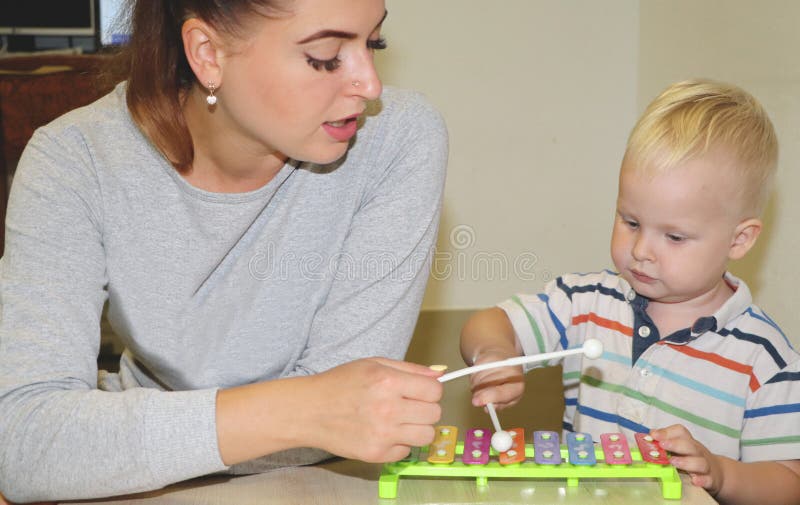 L'educatore tratta con il bambino nell'asilo Creatività e sviluppo del bambino immagine stock L'educatore tratta con il bambino nell'asilo Creatività e sviluppo del bambino immagine stock