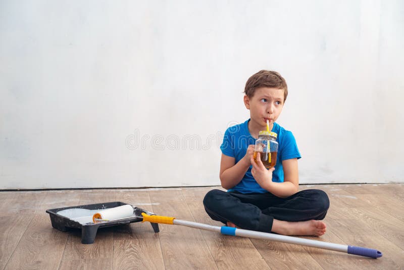 L'enfant boit du thé pendant la réparation du mur le travail de finition dans les lieux de l'artiste peint les murs R?parez de photo libre de droits L'enfant boit du thé pendant la réparation du mur le travail de finition dans les lieux de l'artiste peint les murs R?parez de photo libre de droits