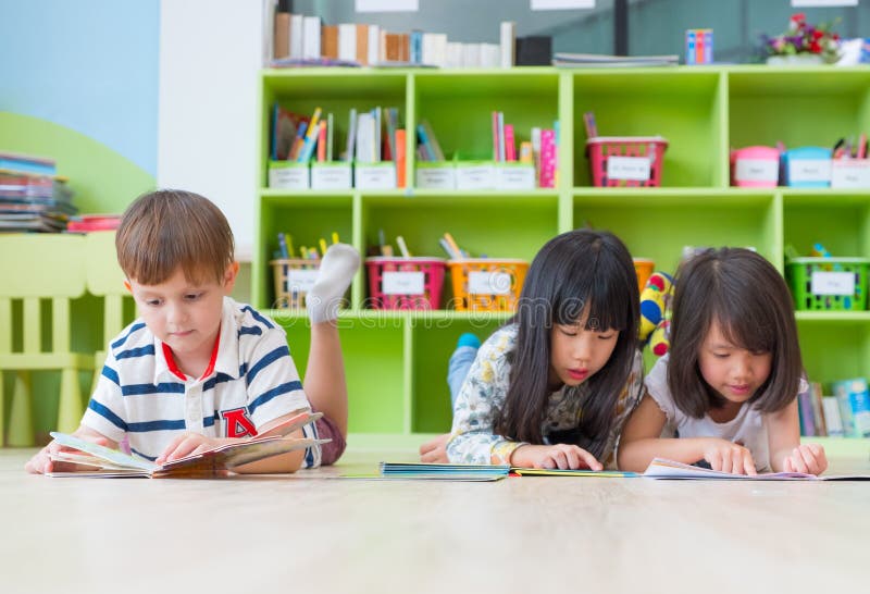 L'enfant de diversité fixent sur le livre de conte de plancher et de lecture dans le prescho photo libre de droits L'enfant de diversité fixent sur le livre de conte de plancher et de lecture dans le prescho photo libre de droits