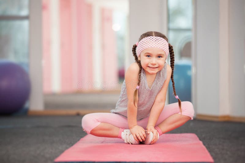 L'enfant de fille faisant la forme physique s'exerce dans le club de santé, s'étirant dans l'exercice images stock L'enfant de fille faisant la forme physique s'exerce dans le club de santé, s'étirant dans l'exercice images stock